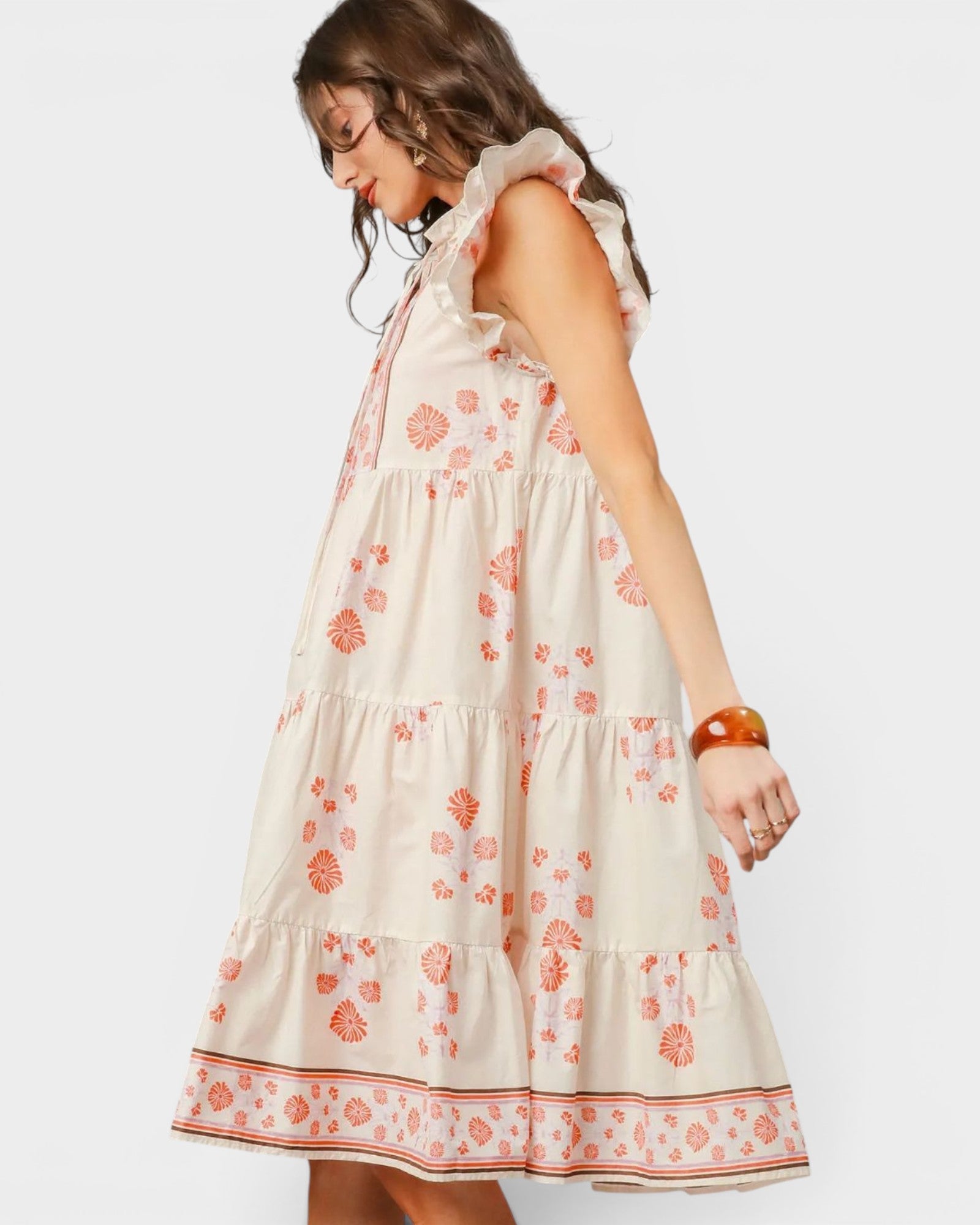 Woman wearing a white dress with orange floral pattern on a white background