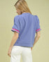 Woman wearing a light purple blouse with pink trim on a beige background