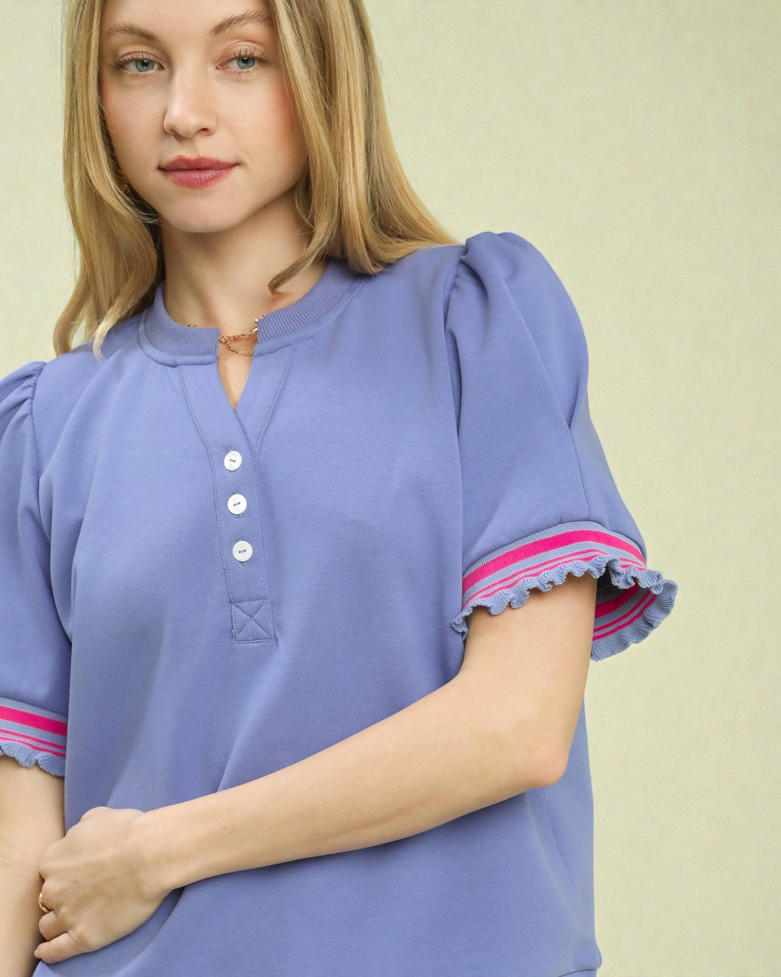Woman wearing a light purple blouse with pink trim on a beige background