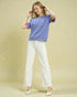 Woman wearing a purple shirt and white pants on a beige background