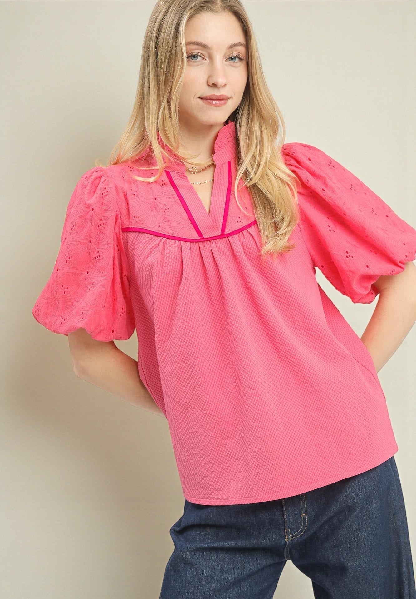 Woman wearing a pink blouse with puff sleeves against a beige background