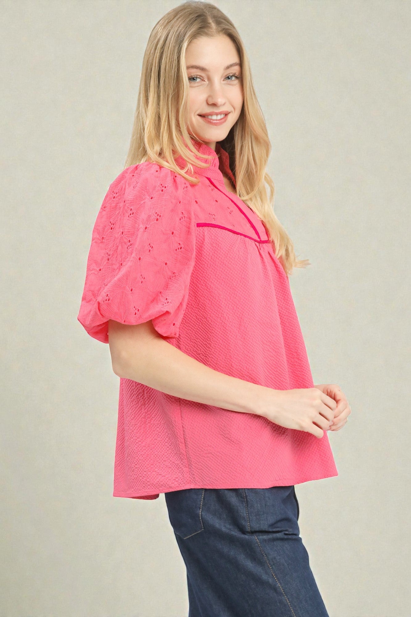 Woman wearing a pink blouse with a subtle pattern on a plain background