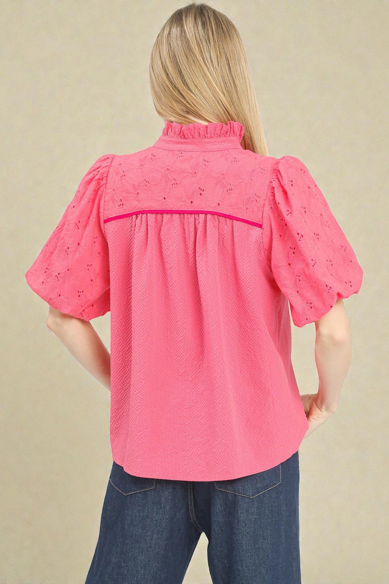 Woman wearing a pink blouse with puff sleeves against a beige background