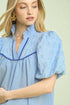 Woman wearing a light blue dress with a subtle pattern on a plain background