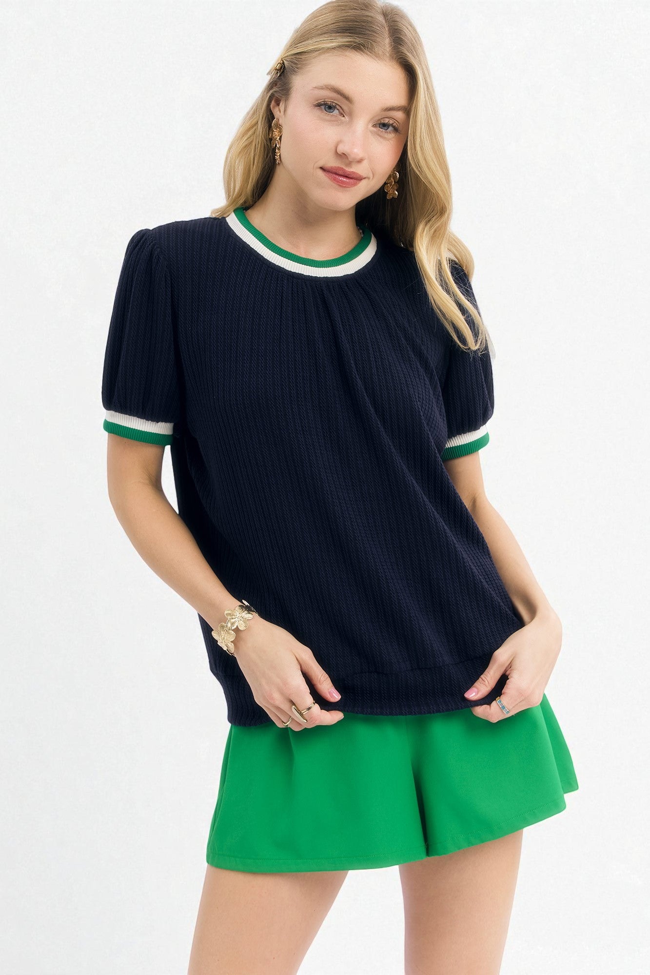 Woman wearing a navy sweater with green trim and a green skirt on a white background