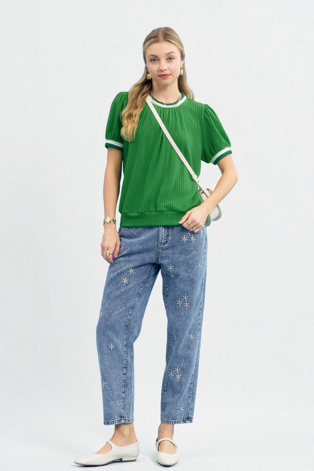 Woman wearing a green shirt and blue jeans with white stars on a white background