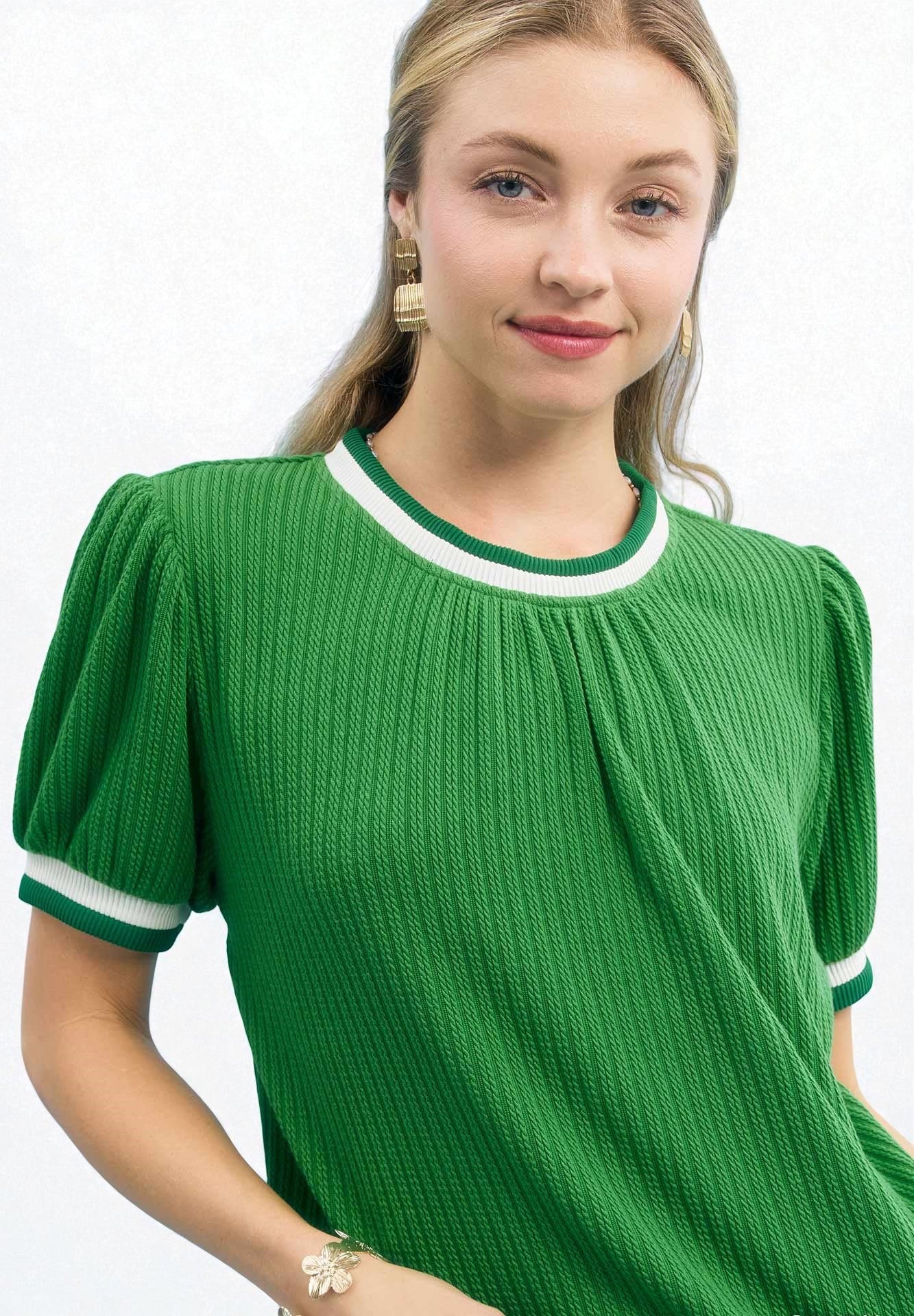Woman wearing a green dress with white trim on a white background
