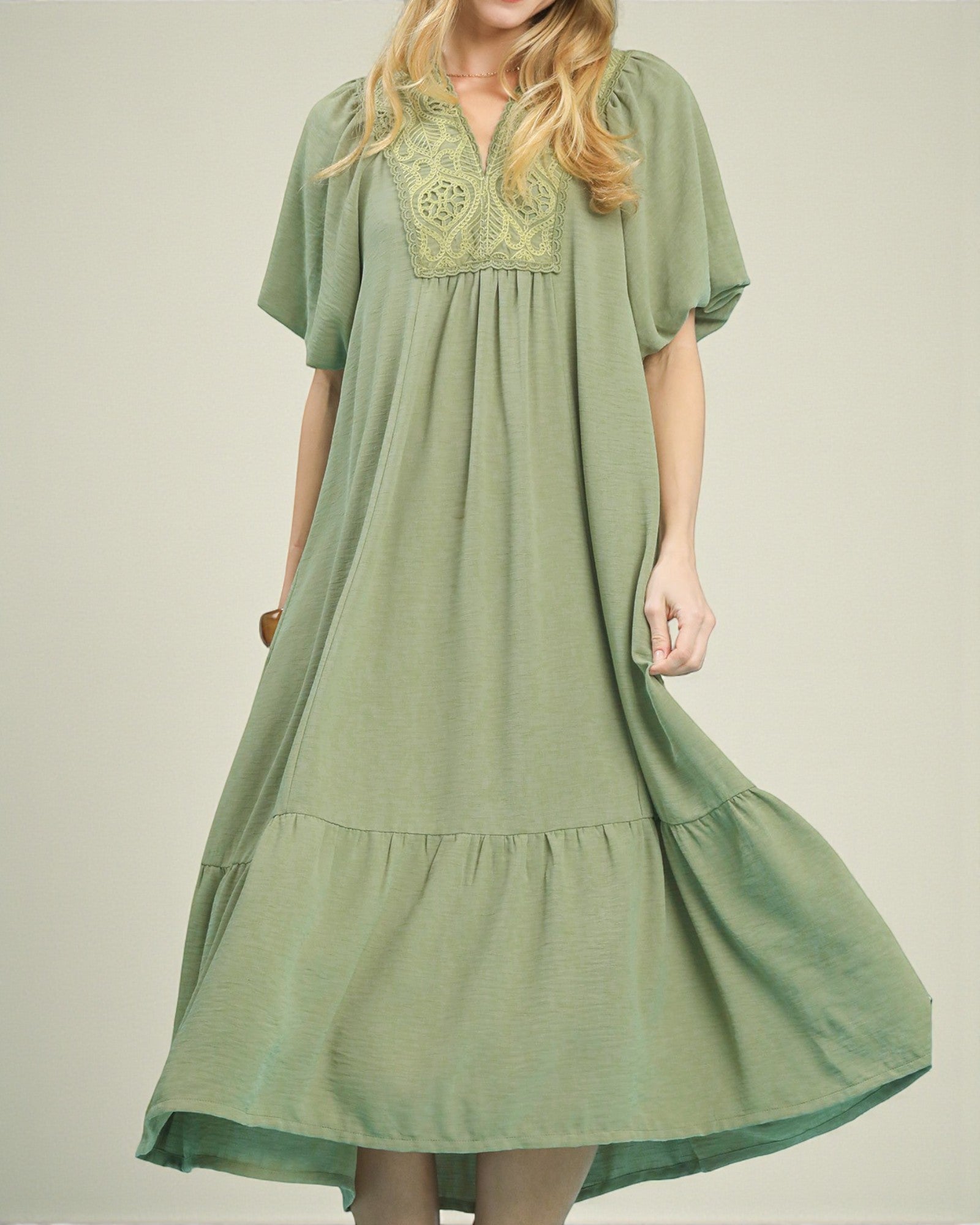 Green dress with lace detailing on a plain background