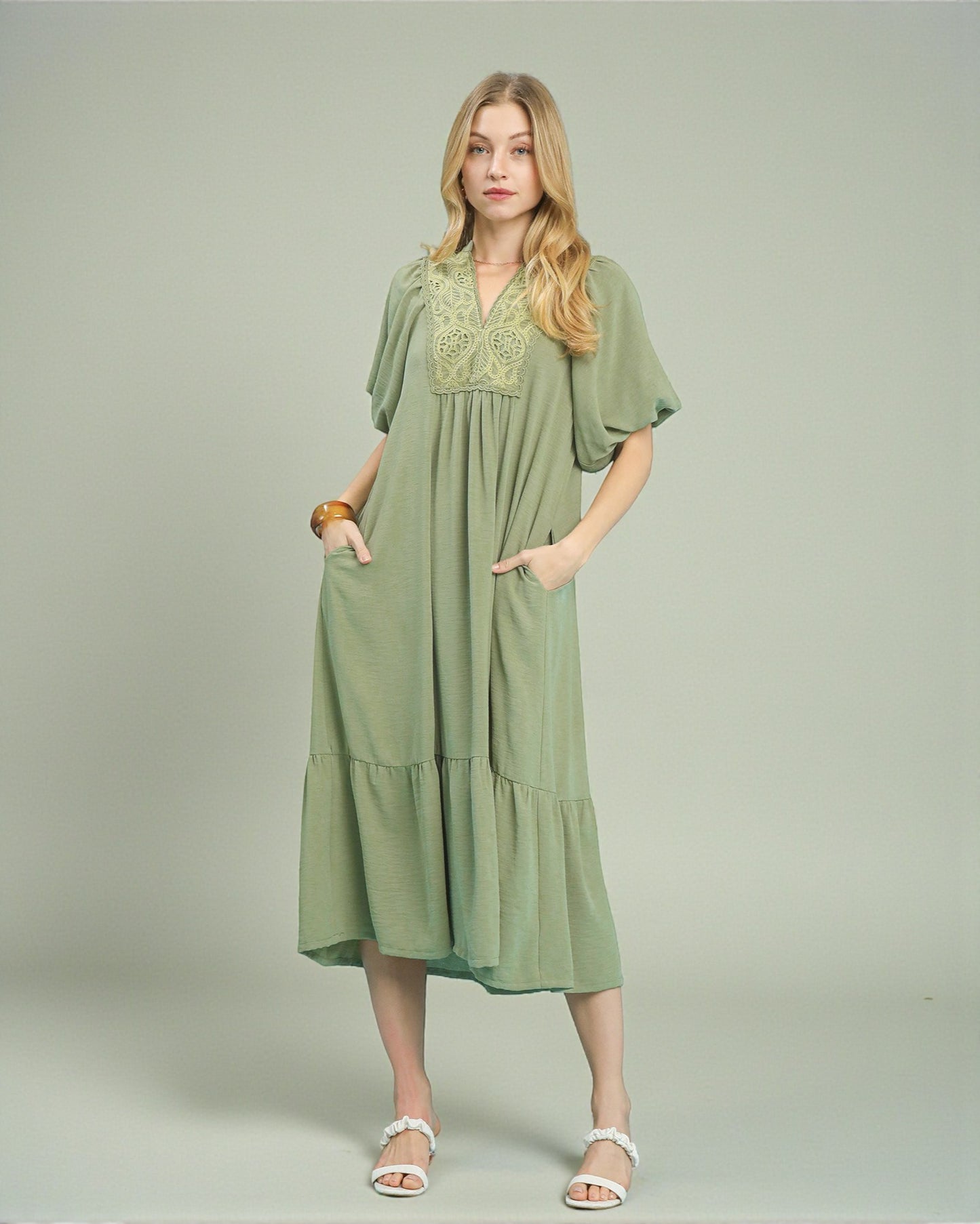 Woman wearing a green dress with embroidery on a plain background