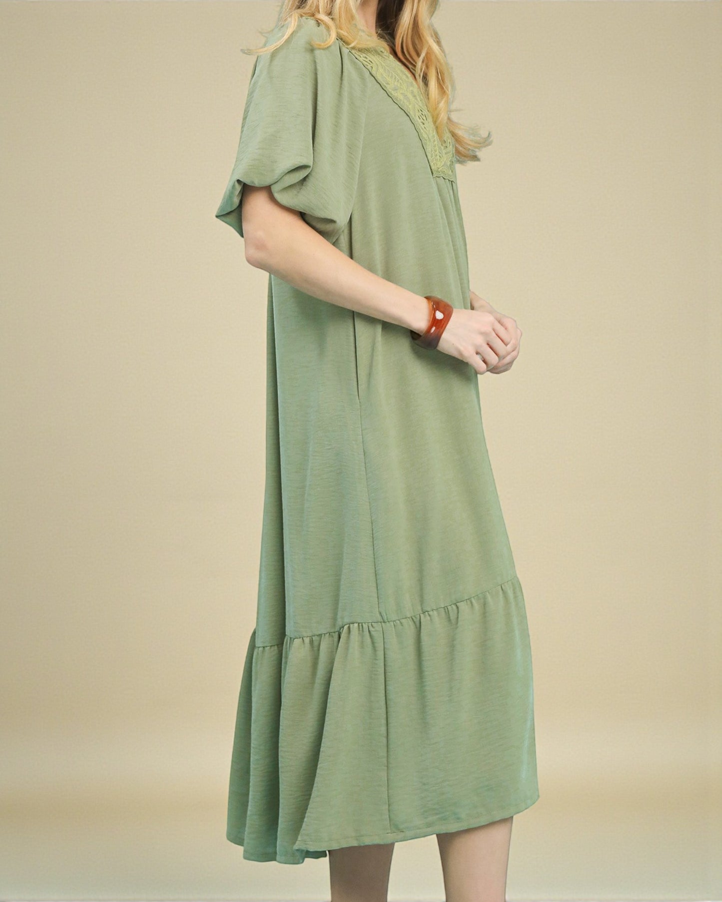 Green dress worn by a person on a beige background