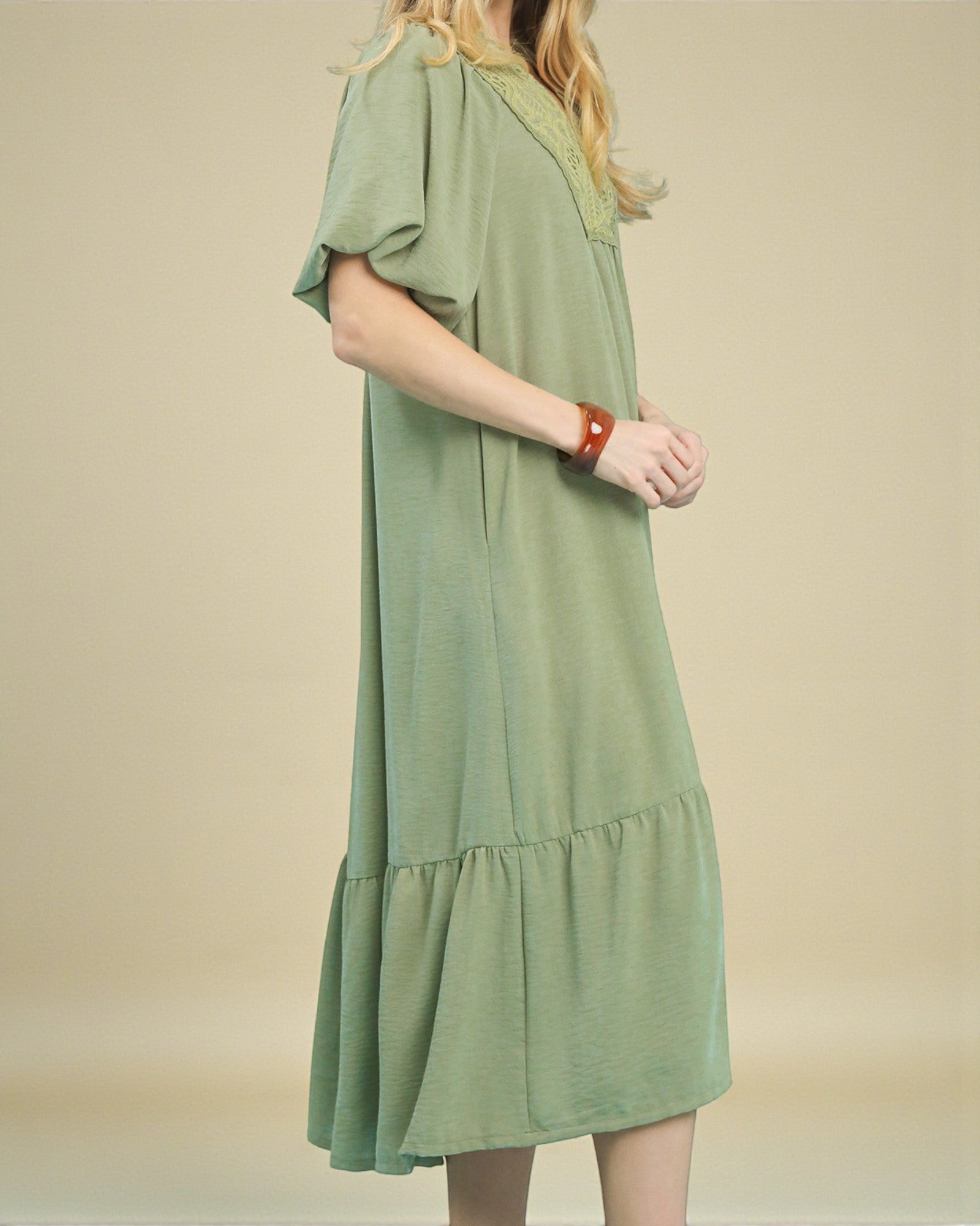 Green dress worn by a person on a beige background