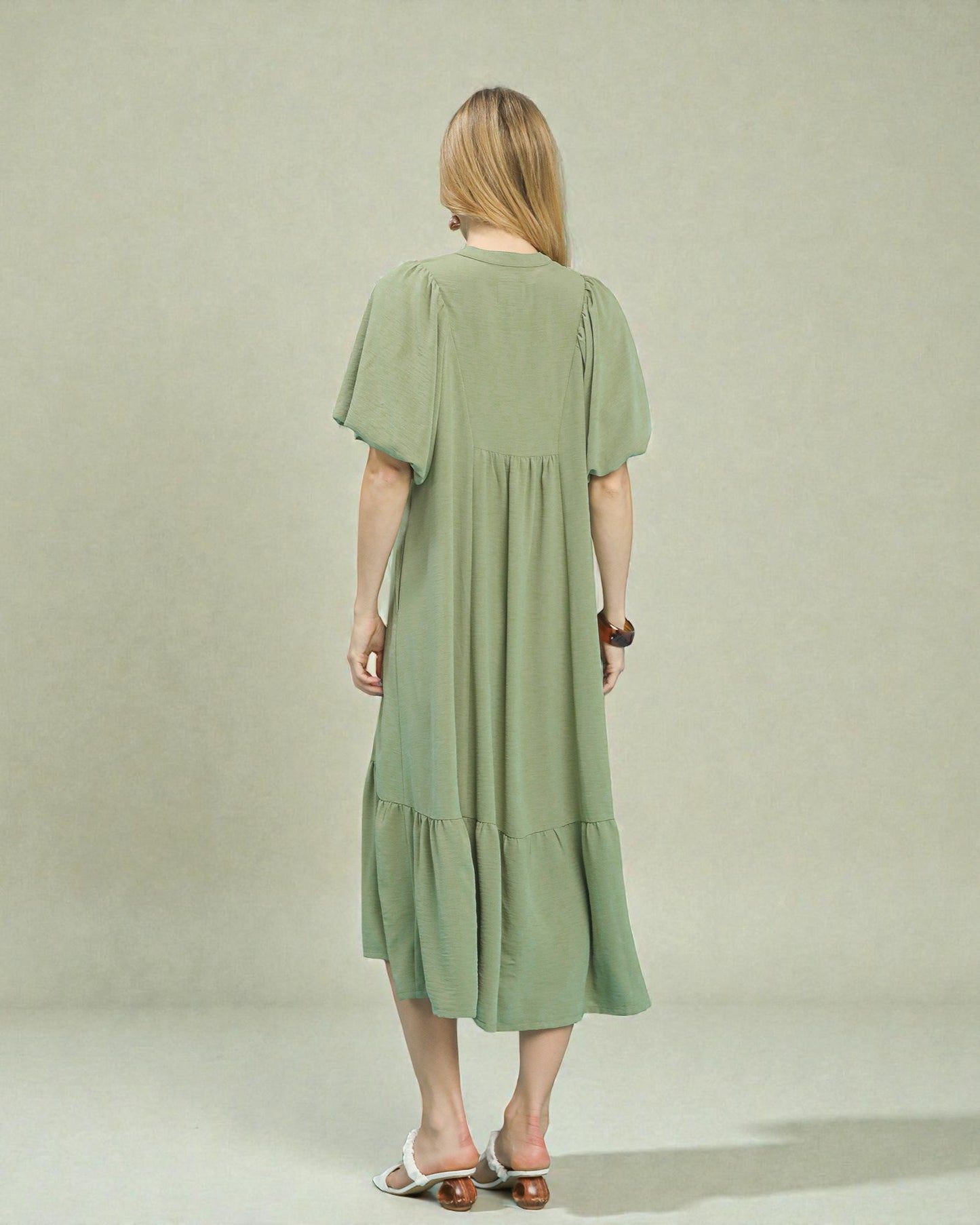 Woman wearing a green dress against a plain background