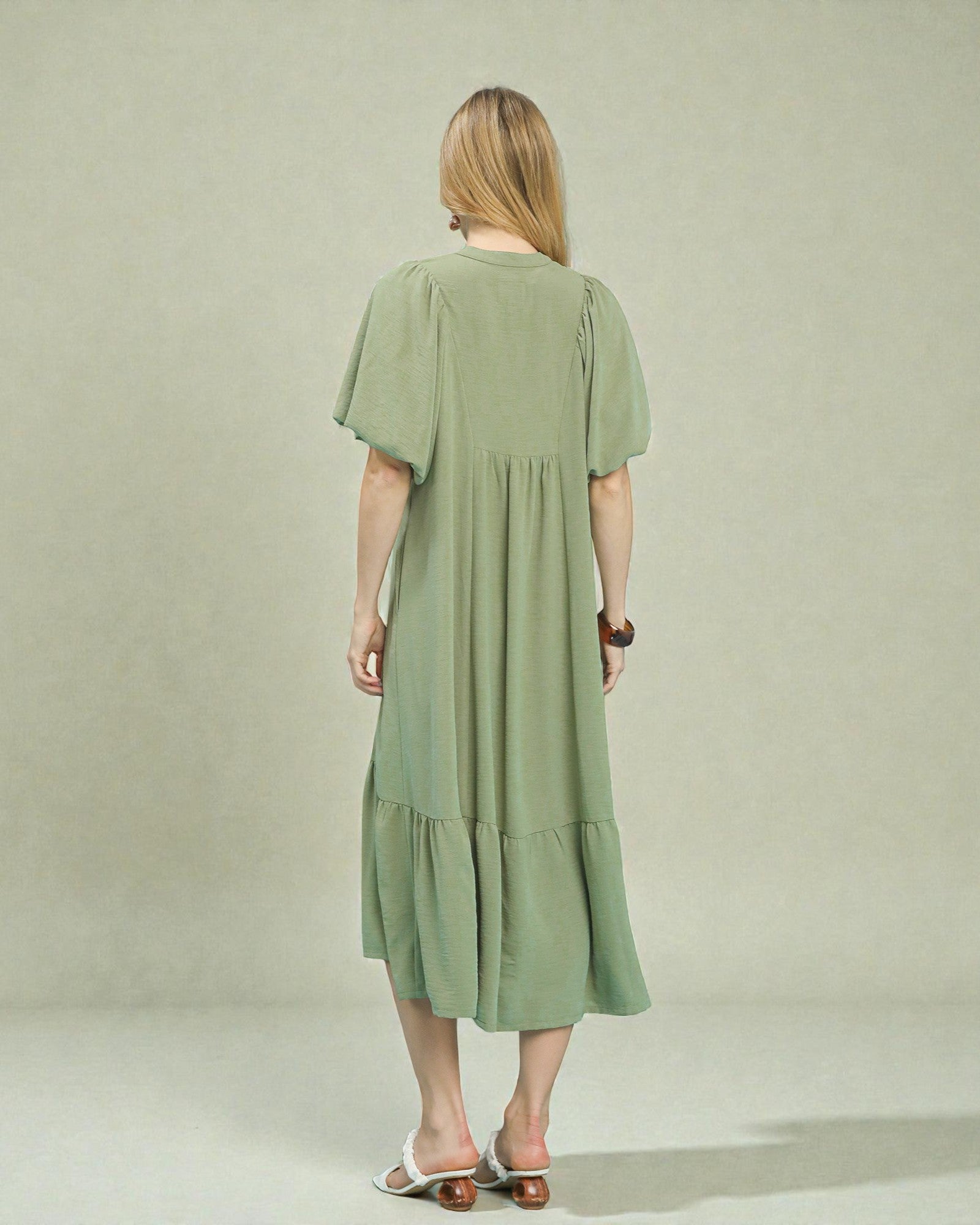 Woman wearing a green dress against a plain background