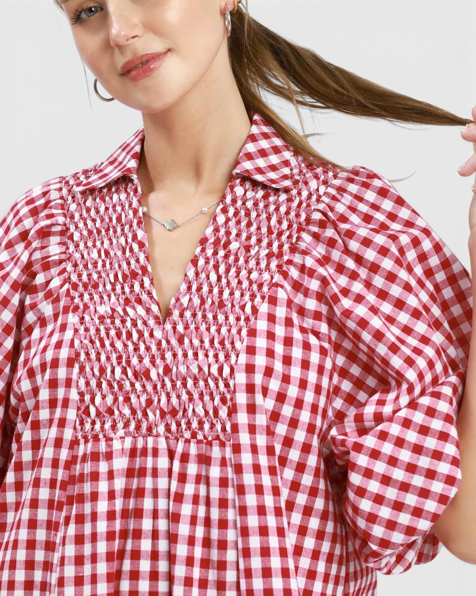 Woman wearing a red and white checkered dress against a plain background