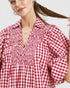 Woman wearing a red and white checkered dress against a plain background
