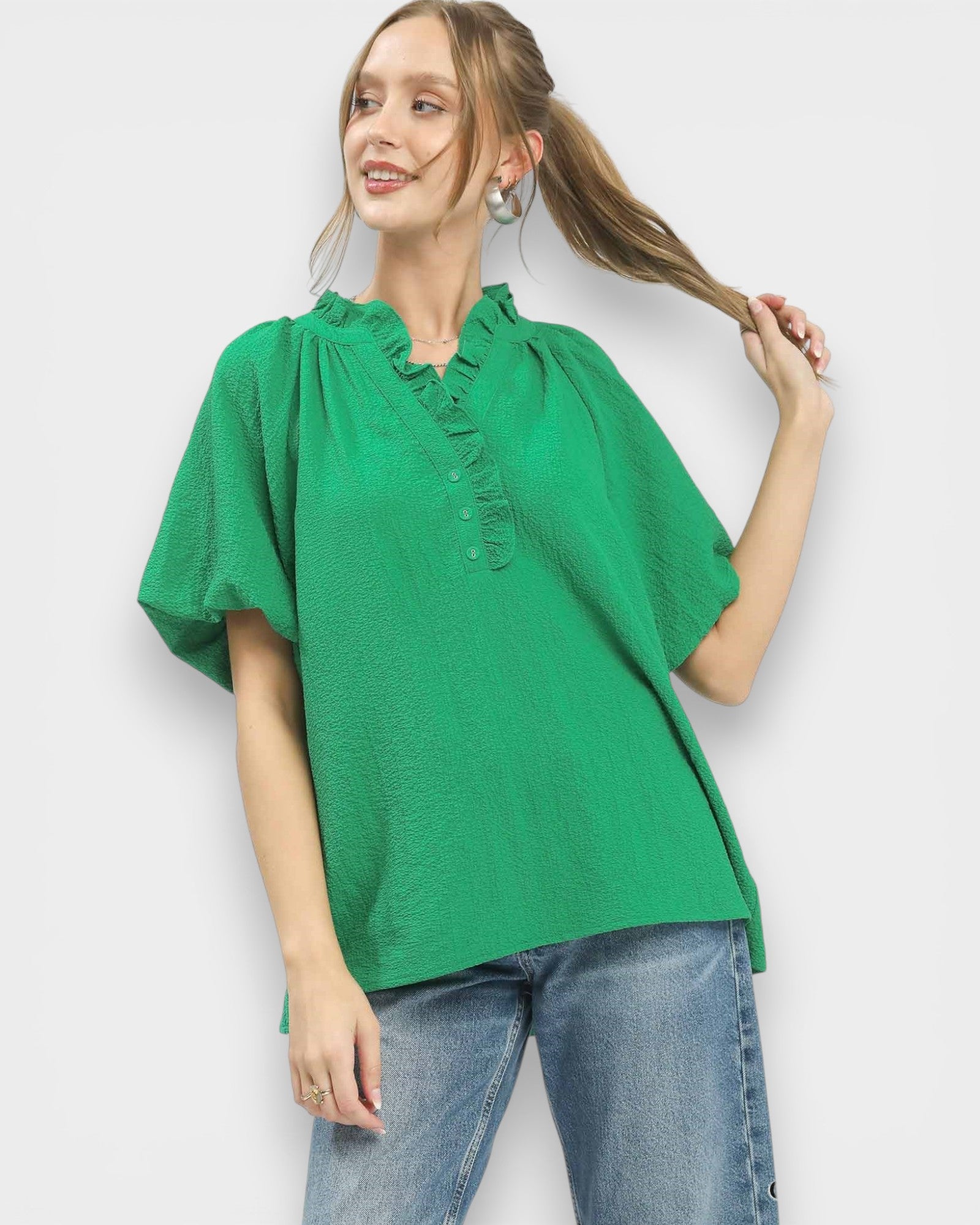 Woman wearing a green blouse and blue jeans against a white background