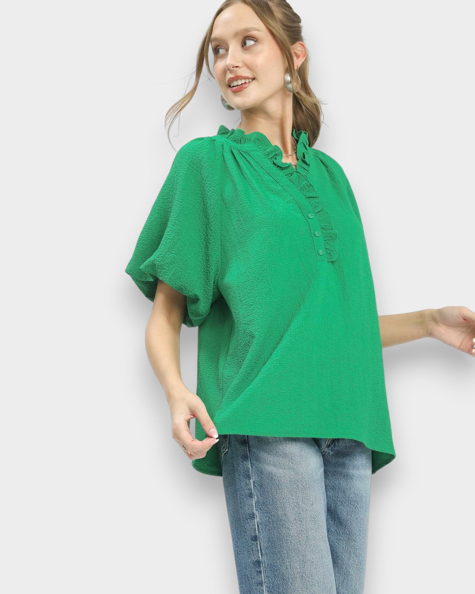 Woman wearing a green blouse and blue jeans on a white background