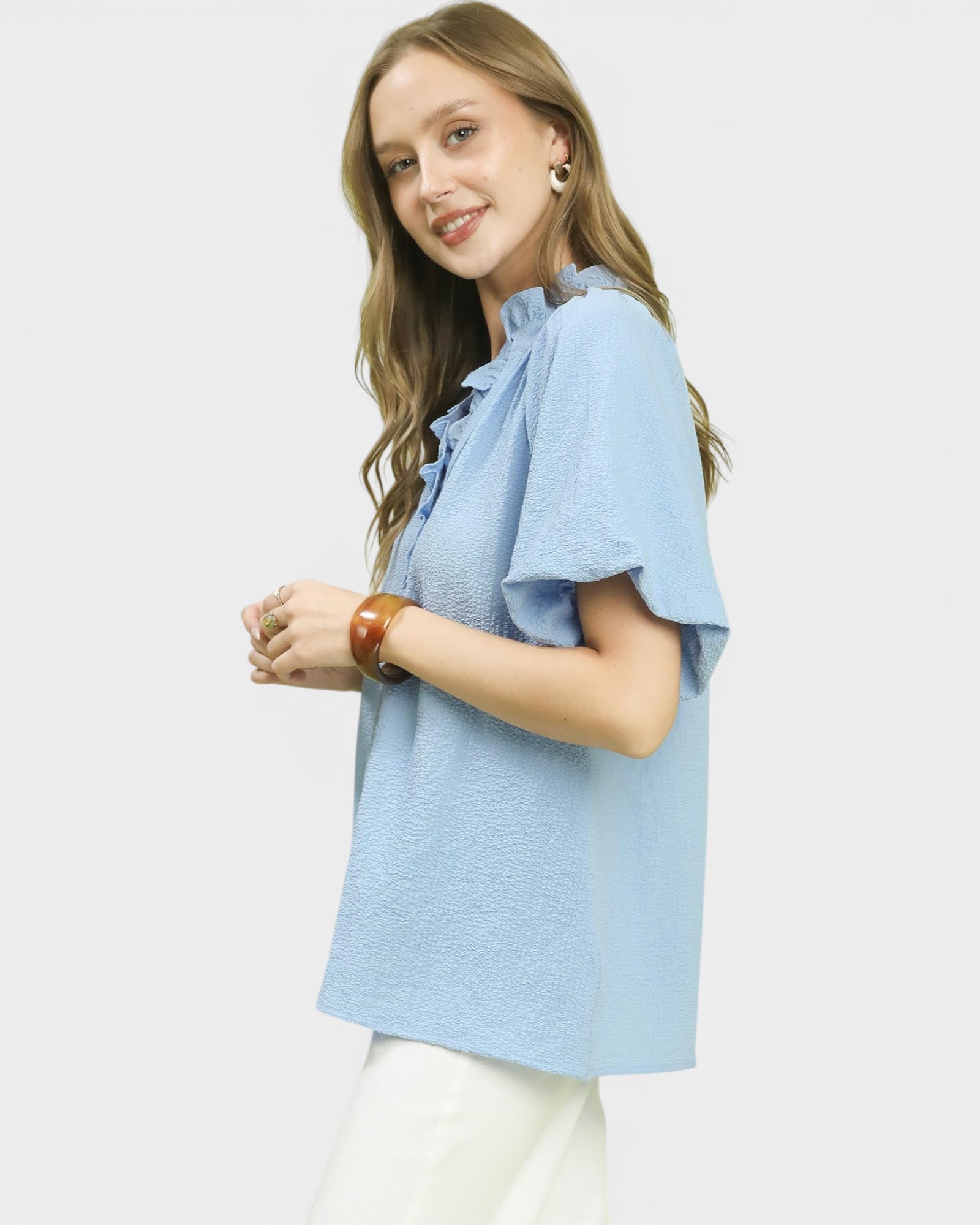 Woman wearing a light blue blouse with ruffled sleeves on a white background