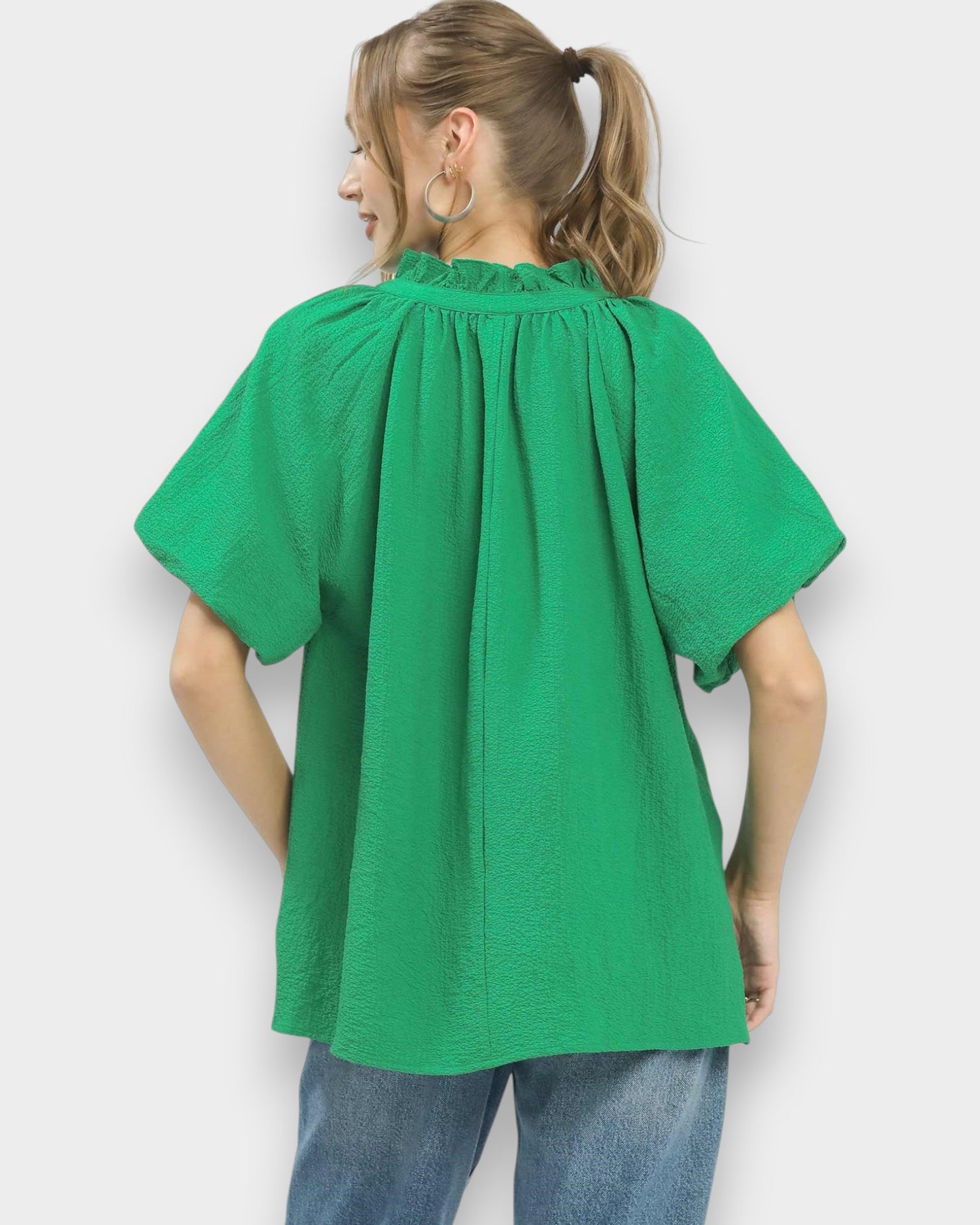 Person wearing a green blouse with short sleeves against a white background