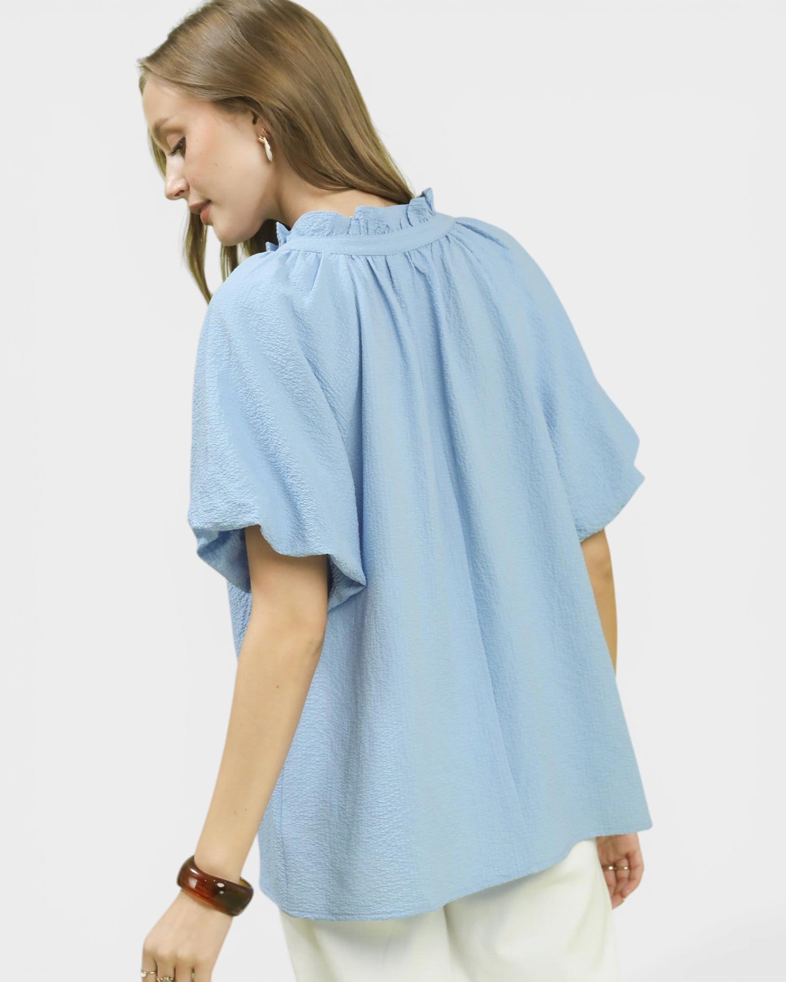 Woman wearing a light blue blouse with a plain background