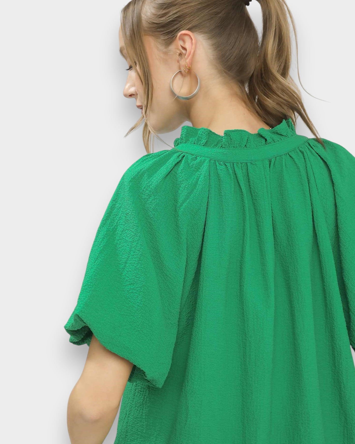 Green blouse worn by a person on a white background