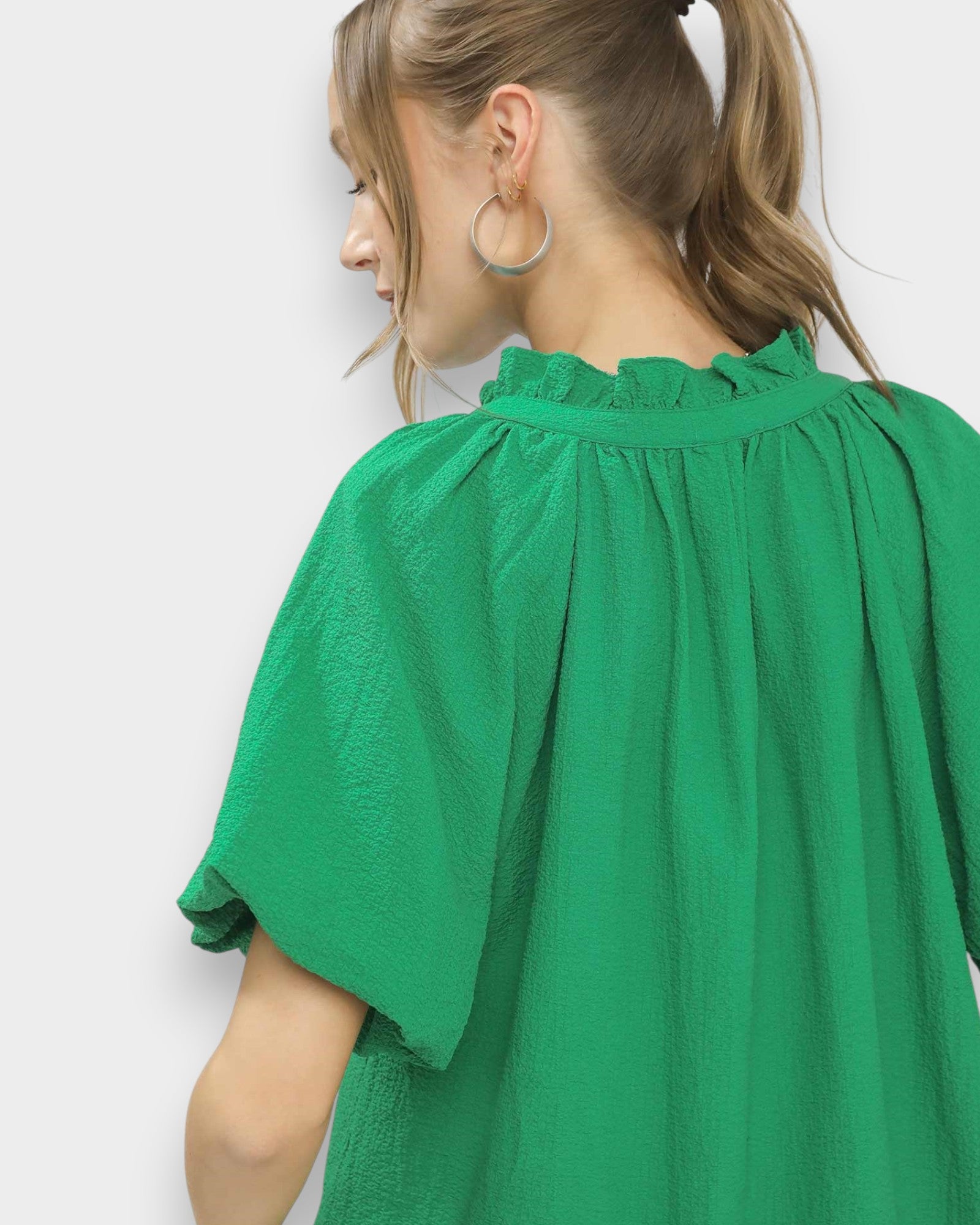 Green blouse worn by a person on a white background