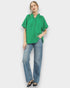 Woman wearing a green top and blue jeans against a white background