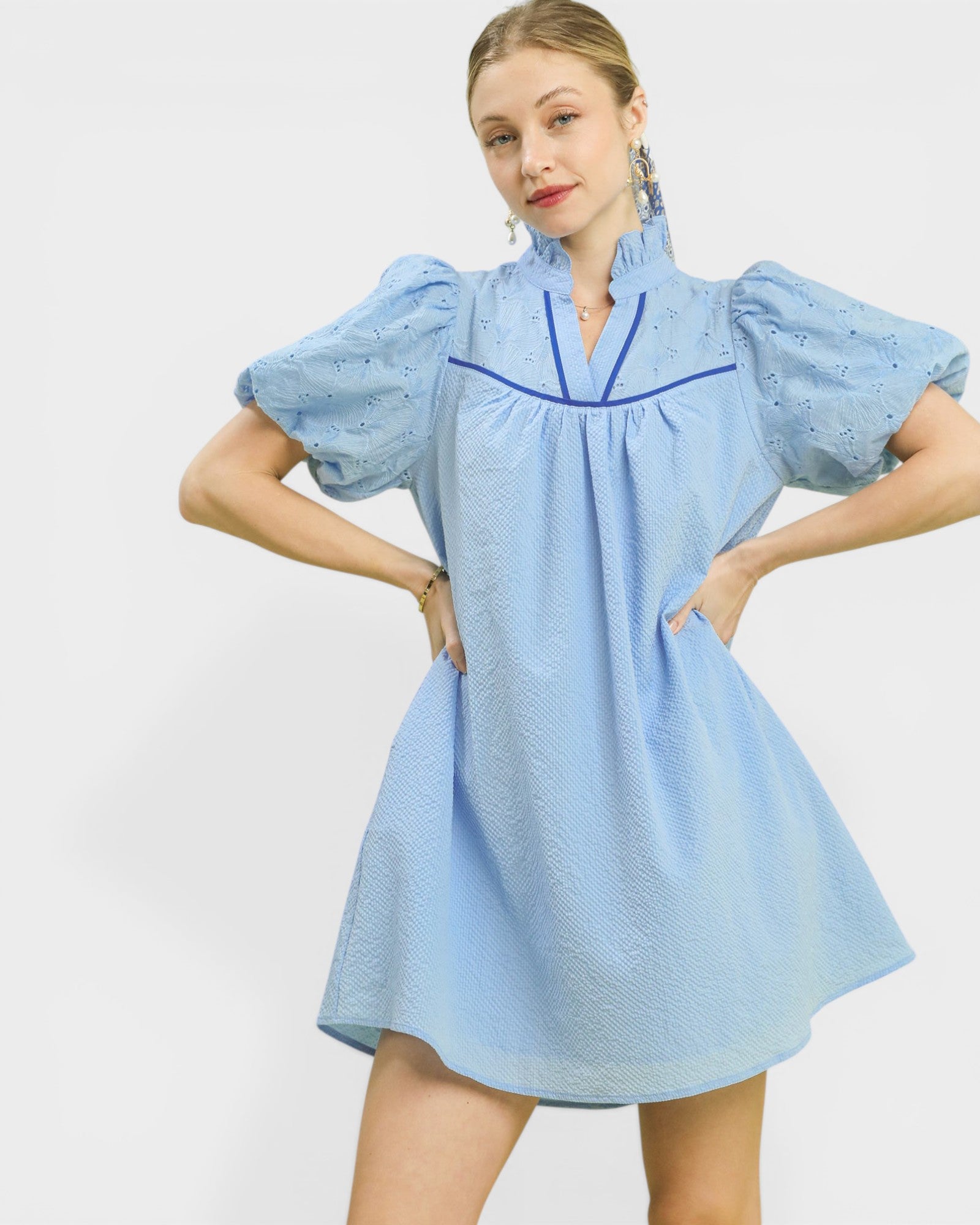 Woman wearing a light blue dress with puffed sleeves on a white background