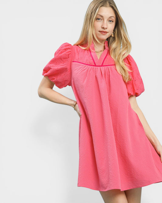 Woman wearing a pink dress with puff sleeves on a white background