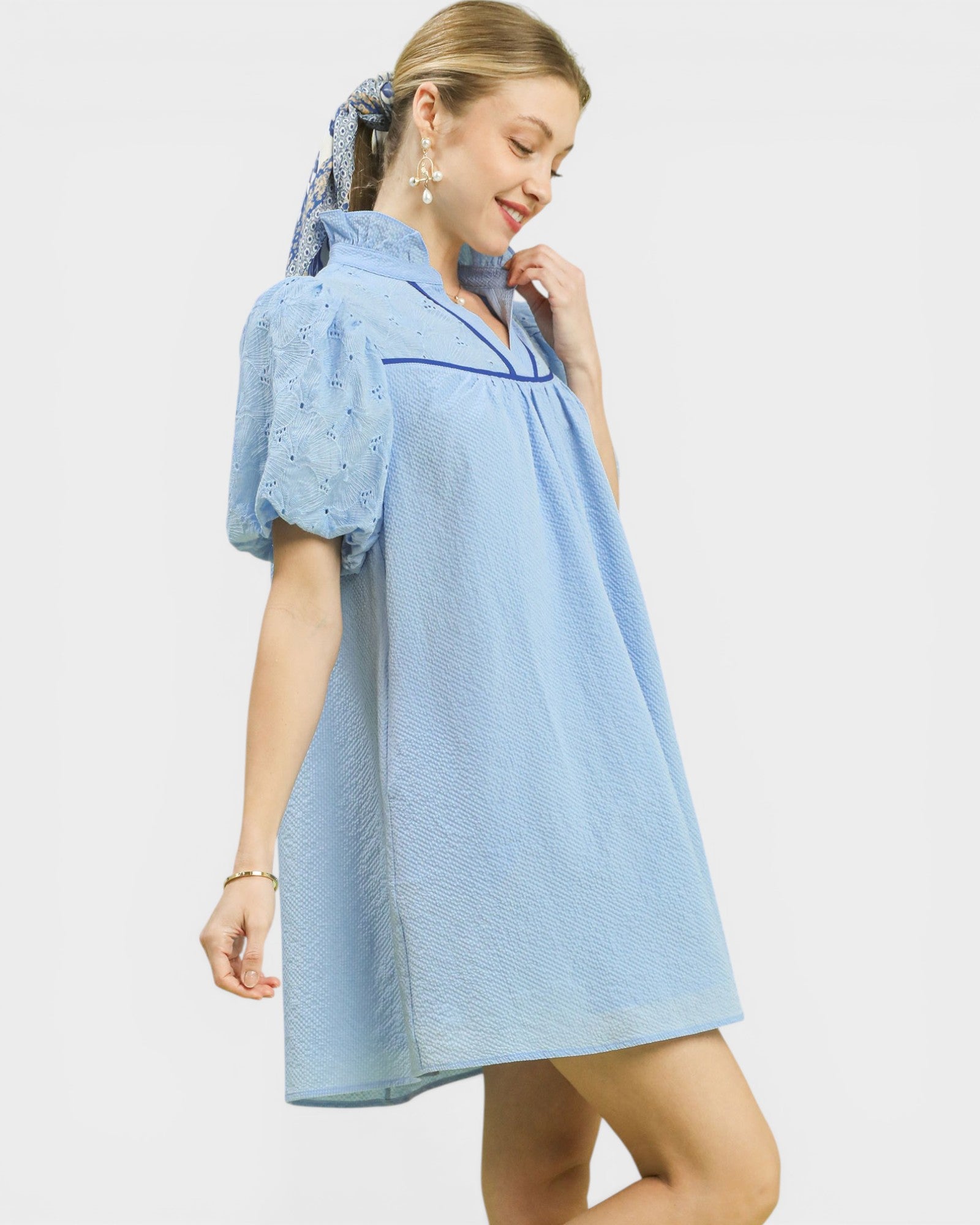 Woman wearing a light blue dress with lace sleeves on a white background