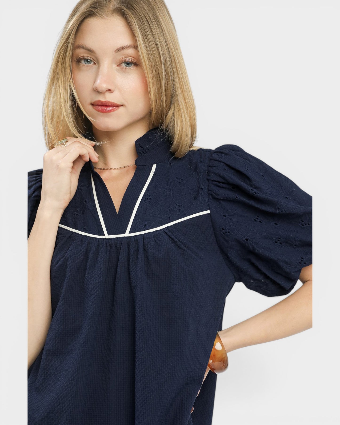 Woman wearing a navy blue dress with white trim on a light gray background