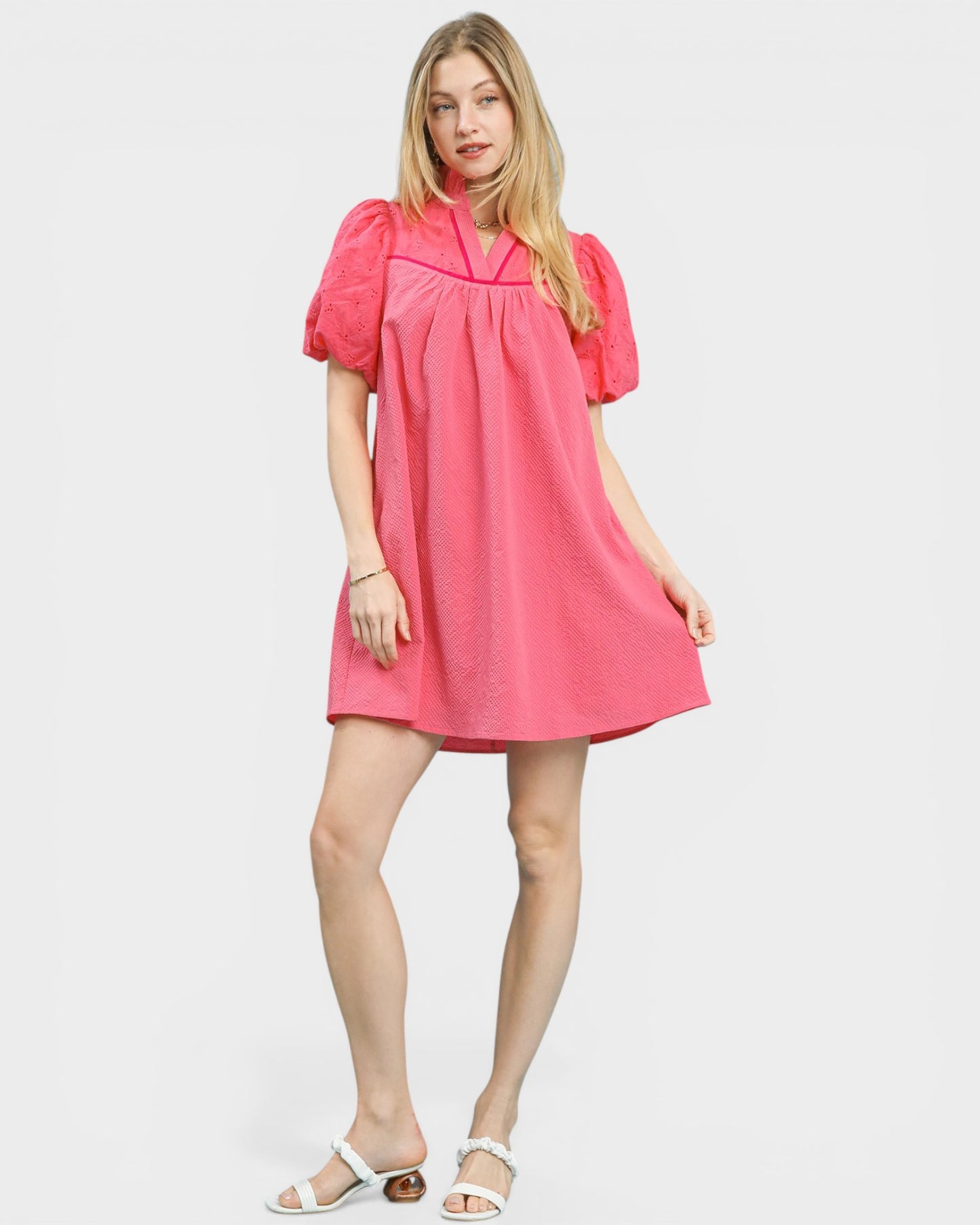 Woman wearing a pink dress with puff sleeves on a white background