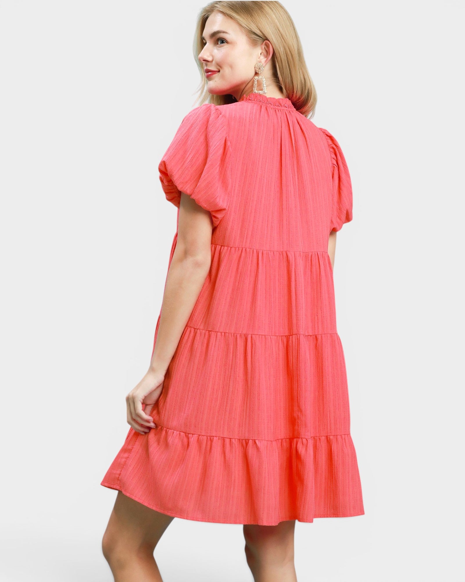 Woman wearing a coral dress on a white background