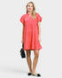 Woman wearing a coral dress on a white background