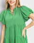 Woman wearing a green dress with puff sleeves against a plain background