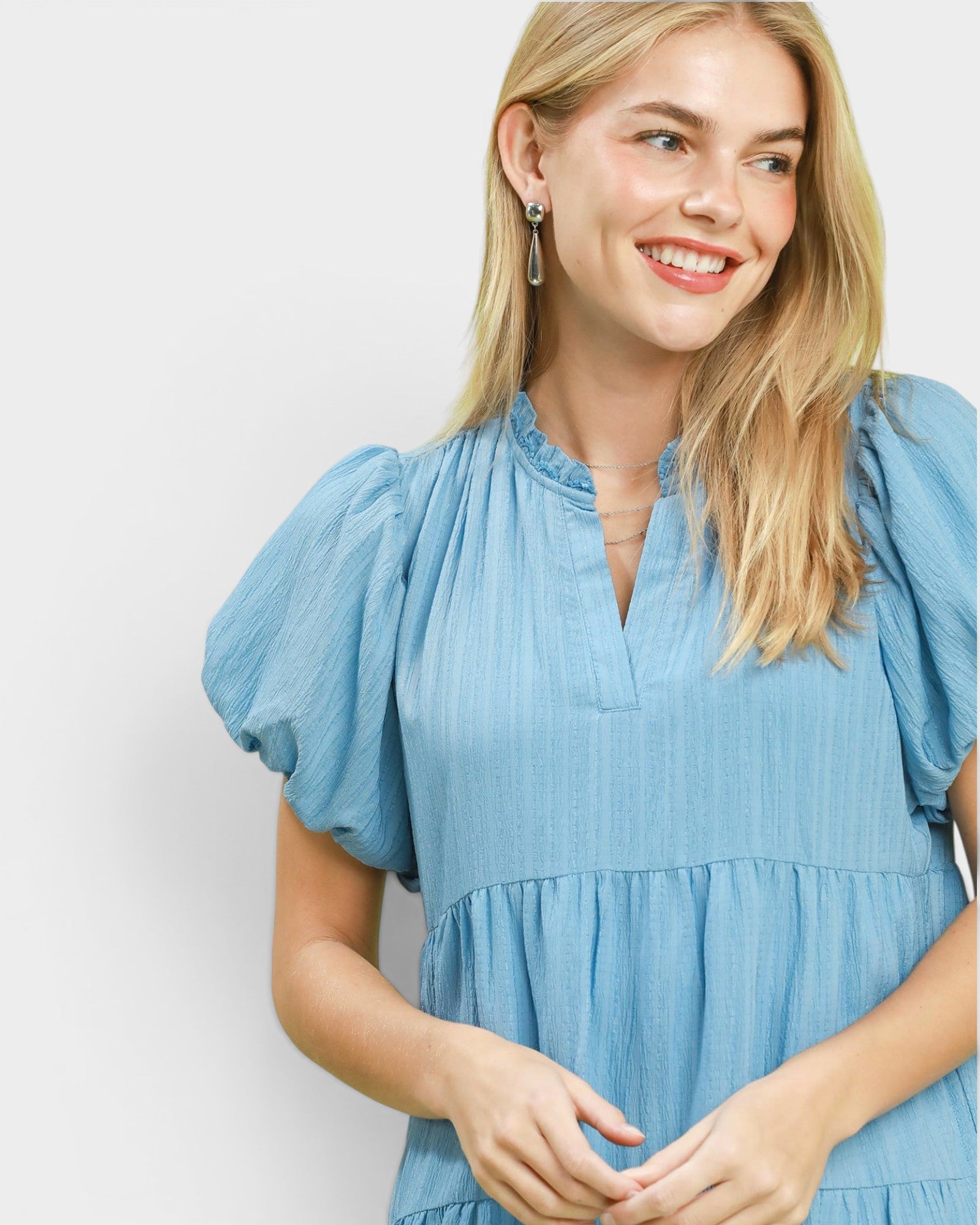 Woman wearing a blue dress with puffed sleeves against a white background