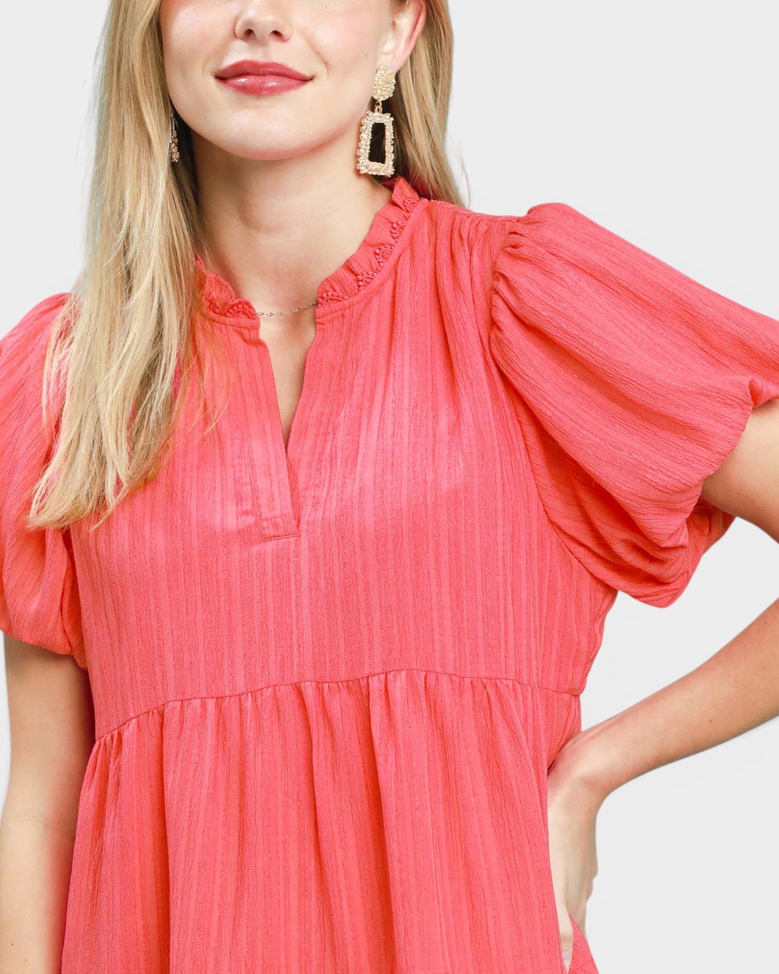Woman wearing a coral dress with a plain background