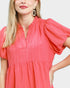 Woman wearing a coral dress with a plain background