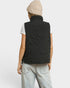 Person wearing a black quilted vest on a white background