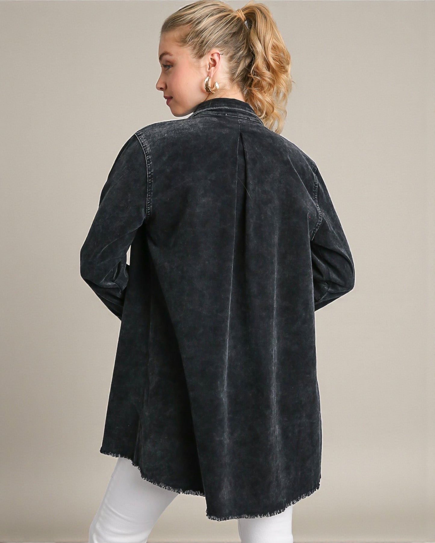 Person wearing a black denim jacket on a beige background