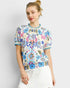Woman wearing a colorful floral-patterned top against a plain background