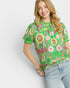 Woman wearing a green floral blouse against a white background