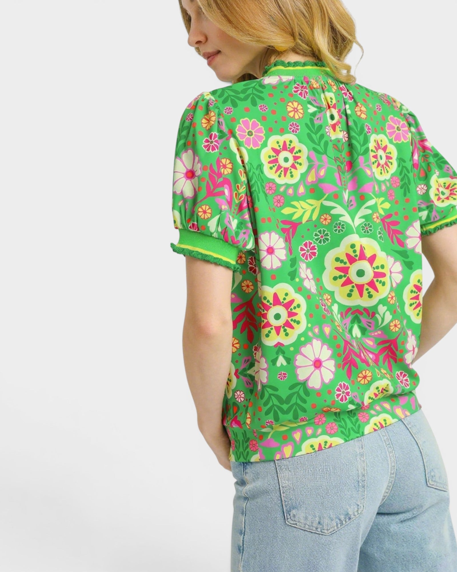 Woman wearing a green floral patterned shirt on a white background