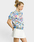 Woman wearing a colorful floral-patterned top and white skirt on a light gray background
