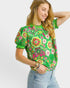 Woman wearing a green floral embroidered blouse against a white background