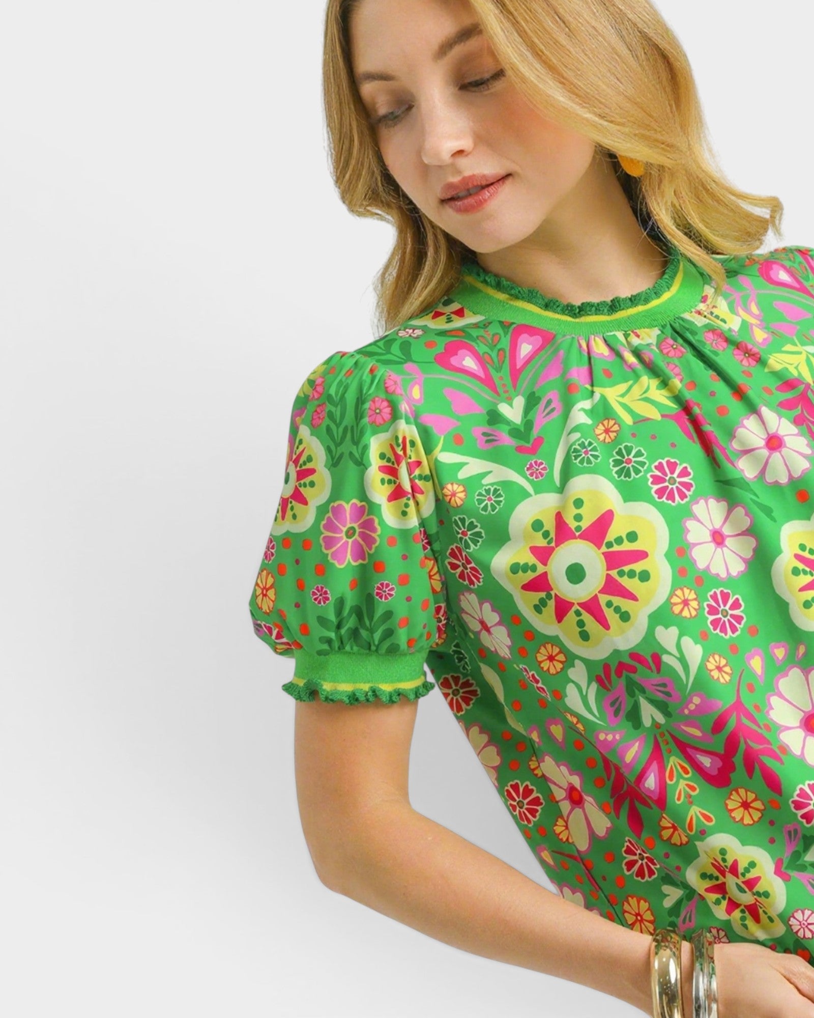 Woman wearing a green floral blouse with a white background