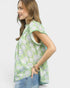 Woman wearing a green floral blouse against a white background