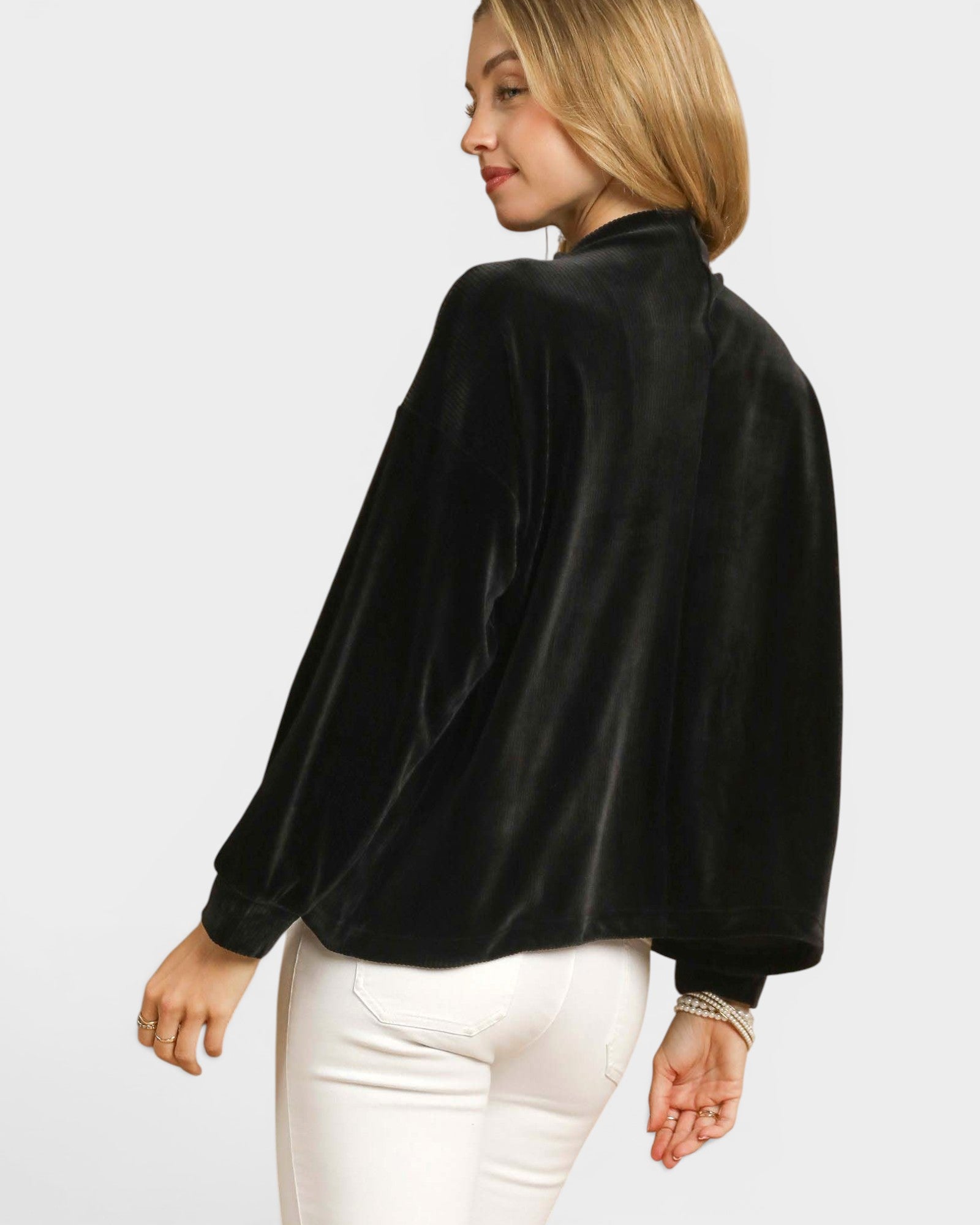 Woman wearing a black blouse and white pants on a plain background
