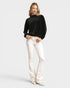 Woman wearing a black top and white pants on a light gray background