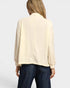 Person wearing a beige blouse and dark blue jeans on a white background